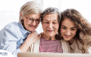 Three generations embrace and look at a computer, representing the sandwich generation.