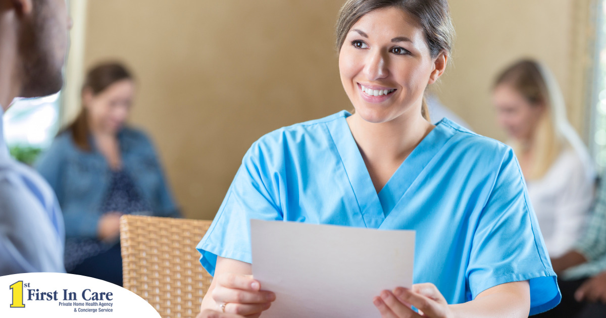 A woman in scrubs holds a paper while interviewing with someone else, representing how a solid caregiver resume can get you to an interview.