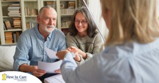 An older couple receives and considers papers from a woman, representing someone considering long-term care insurance.