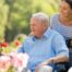 A caregiver takes a senior outside to visit a garden, highlighting one idea for senior activities.